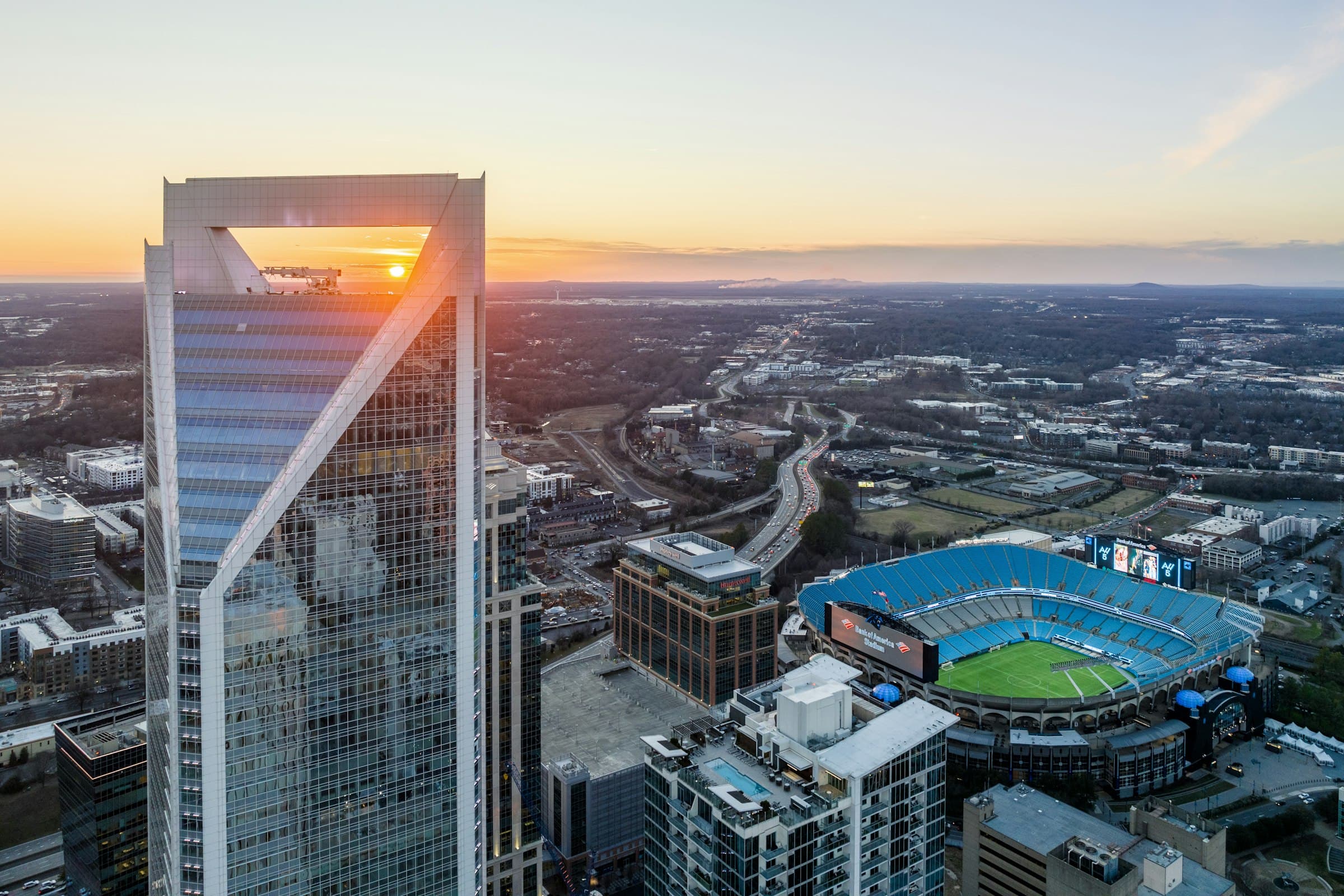 Uptown Charlotte from above at sunset, the Duke Energy Center in front and Bank of America Stadium below